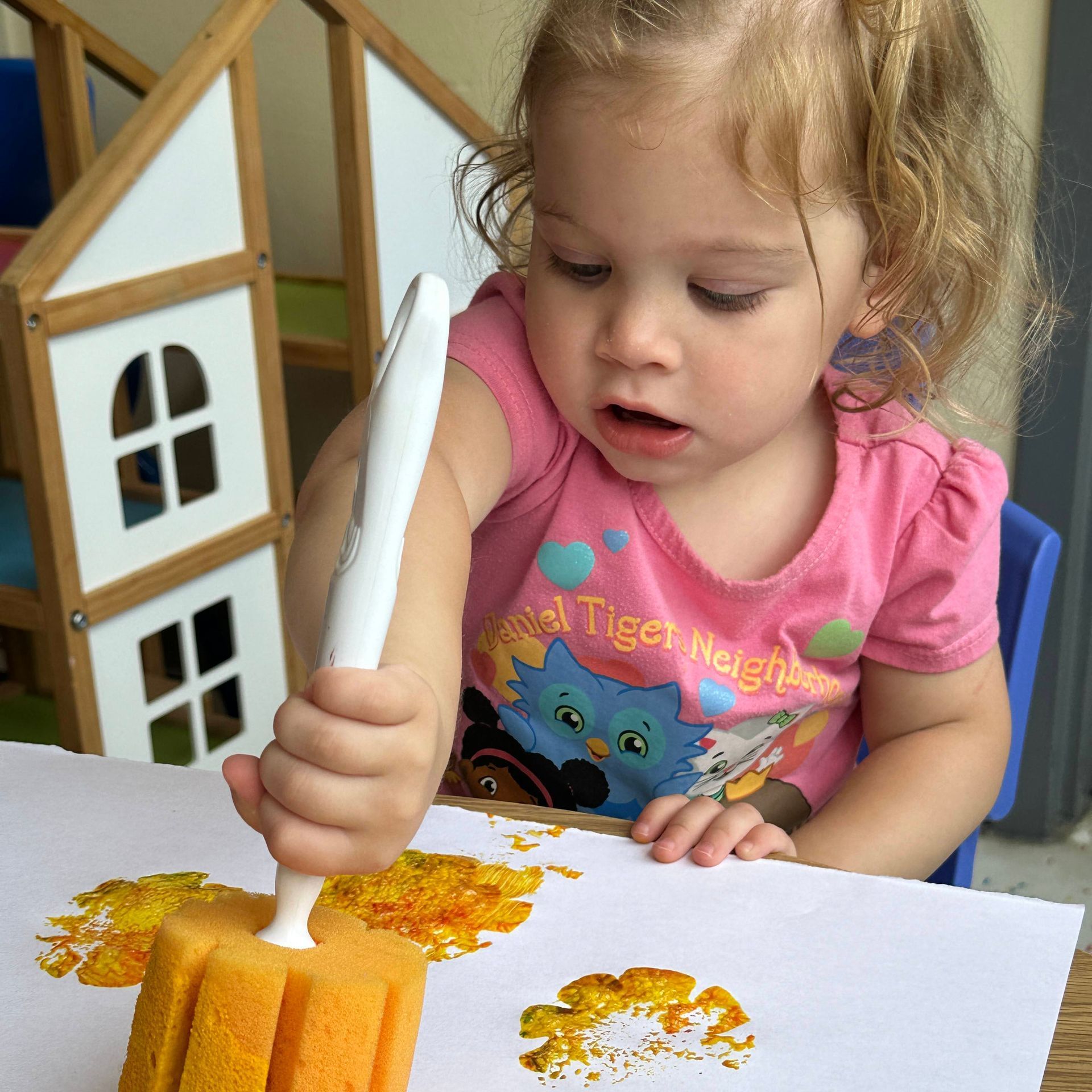 A little girl wearing a pink shirt that says tiger neighbors