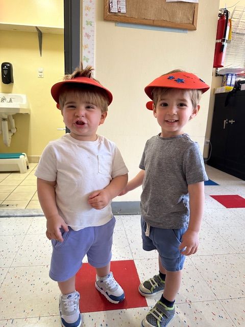 Two little boys wearing hats are standing next to each other