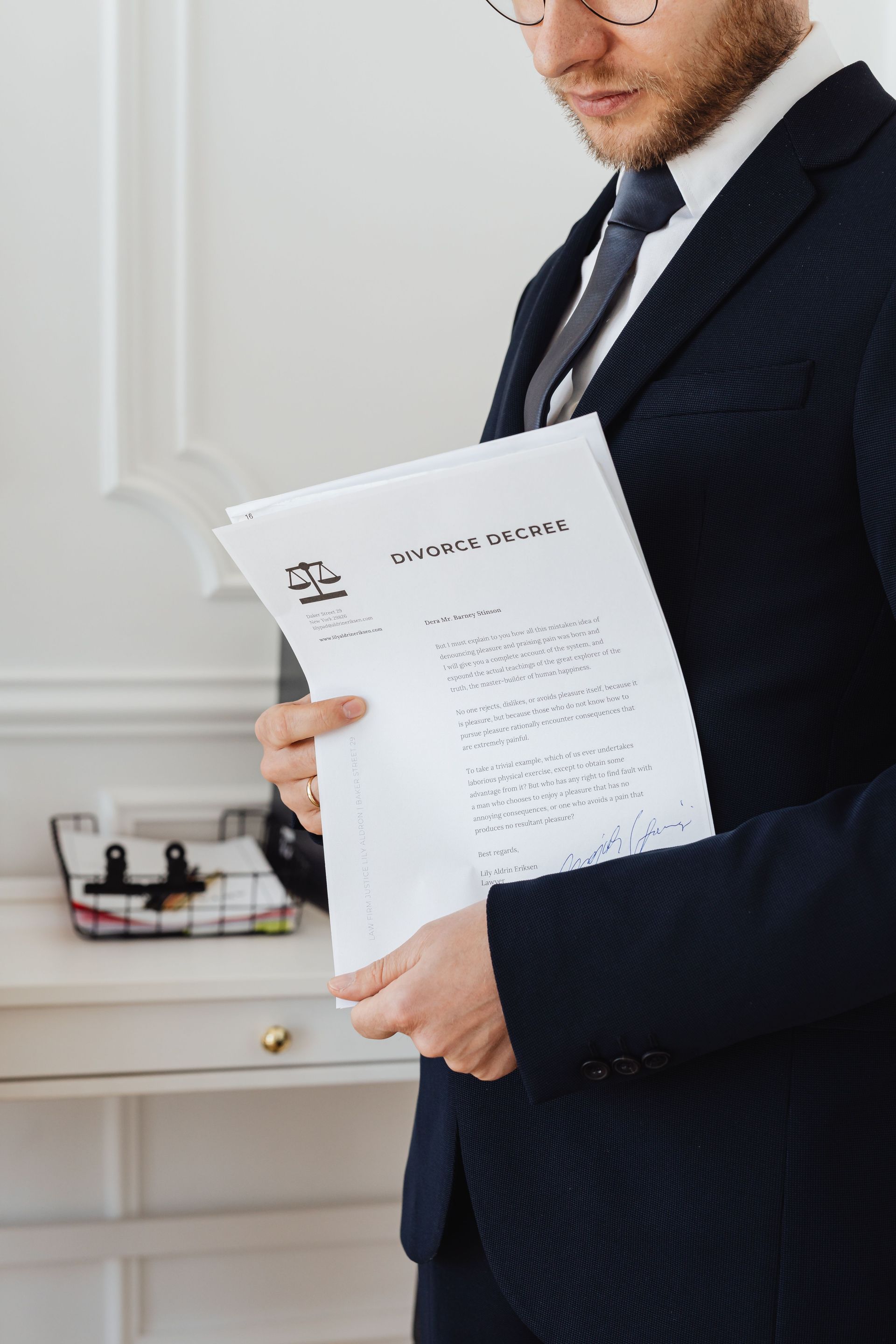 Man in a dark suit holding a document in a bright office setting