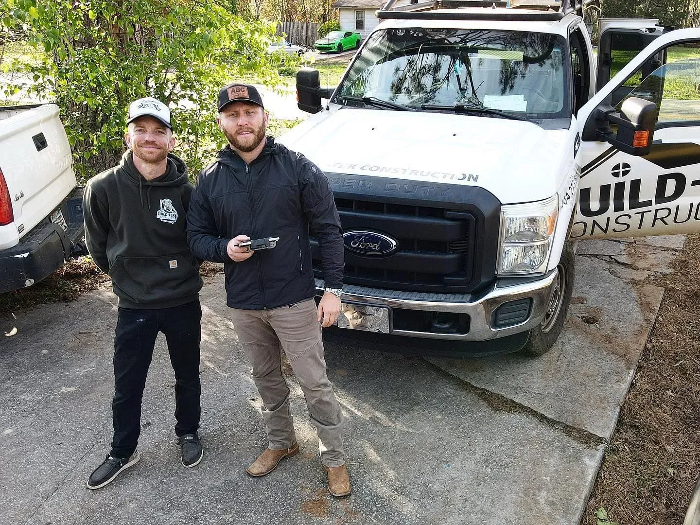 Two men are standing in front of a white truck.