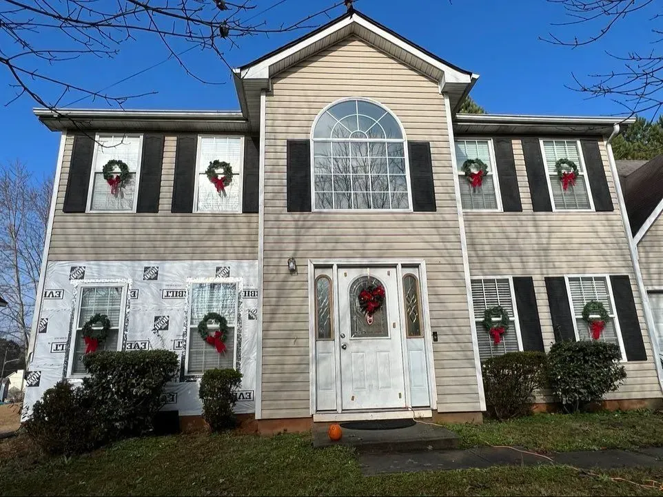 The front of a house with christmas wreaths on the windows