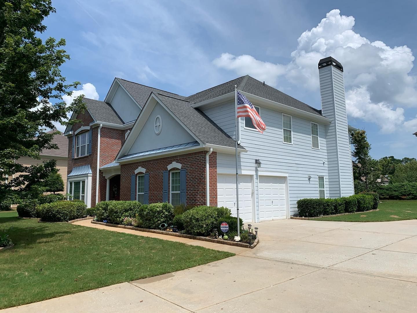A large white house with a brick facade and a gray roof.