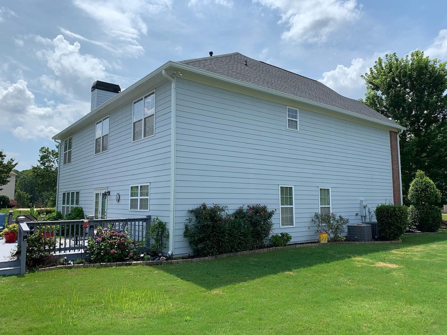 A large white house with a gray roof is sitting on top of a lush green lawn.