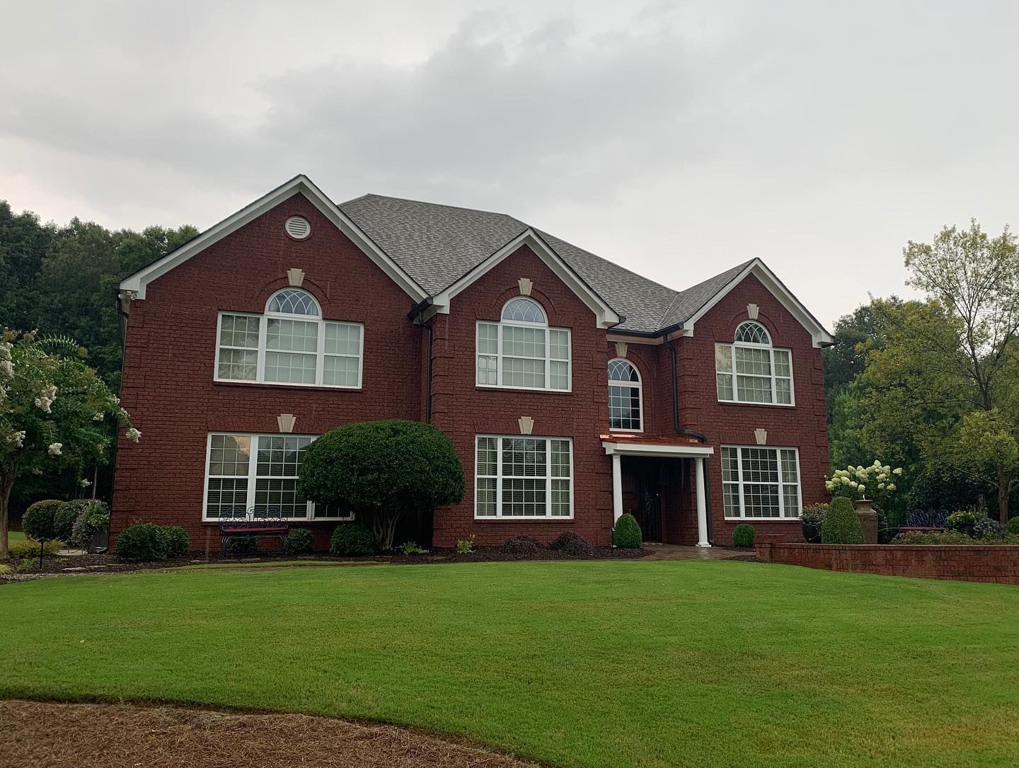 A large brick house with a lush green lawn in front of it