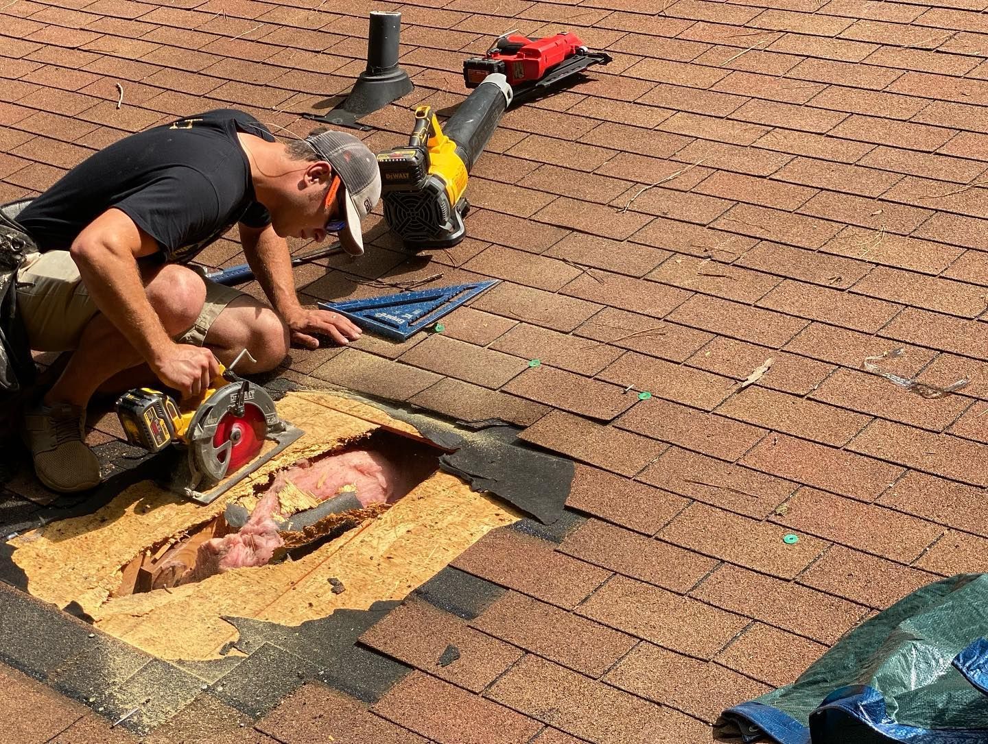 A man is cutting a hole in a roof with a saw.