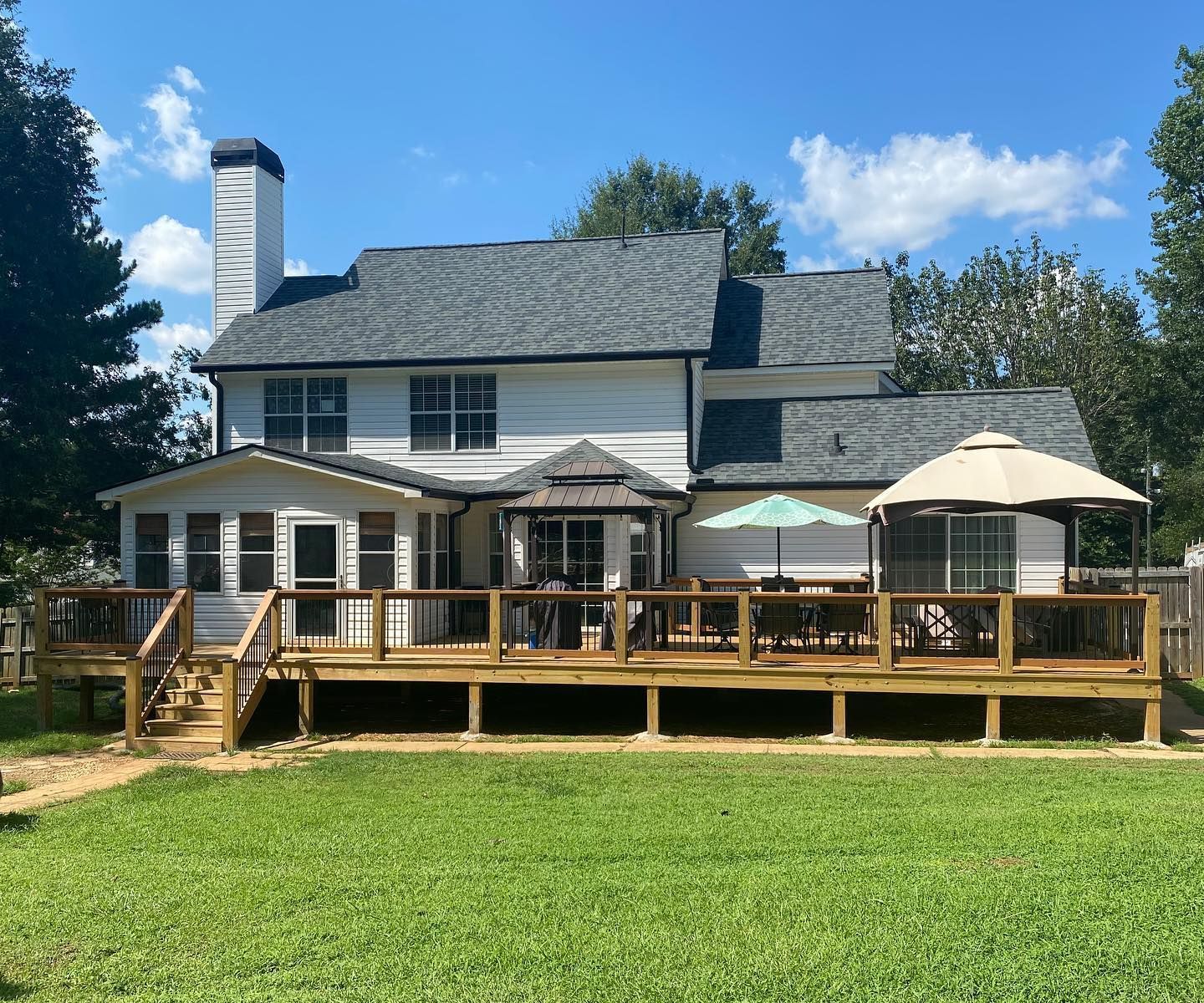 A large white house with a large deck and umbrellas