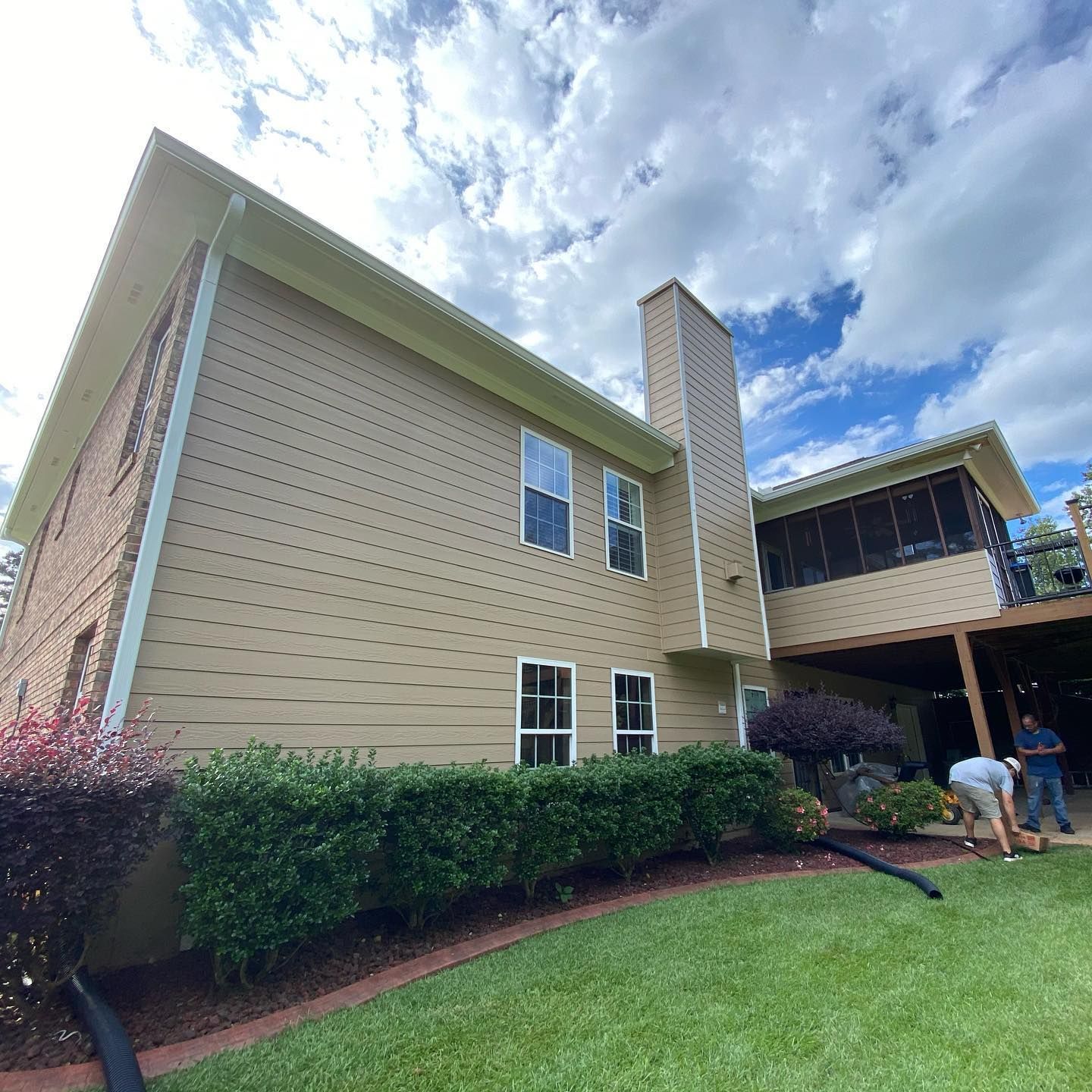 A large house with a lot of windows is sitting on top of a lush green lawn.