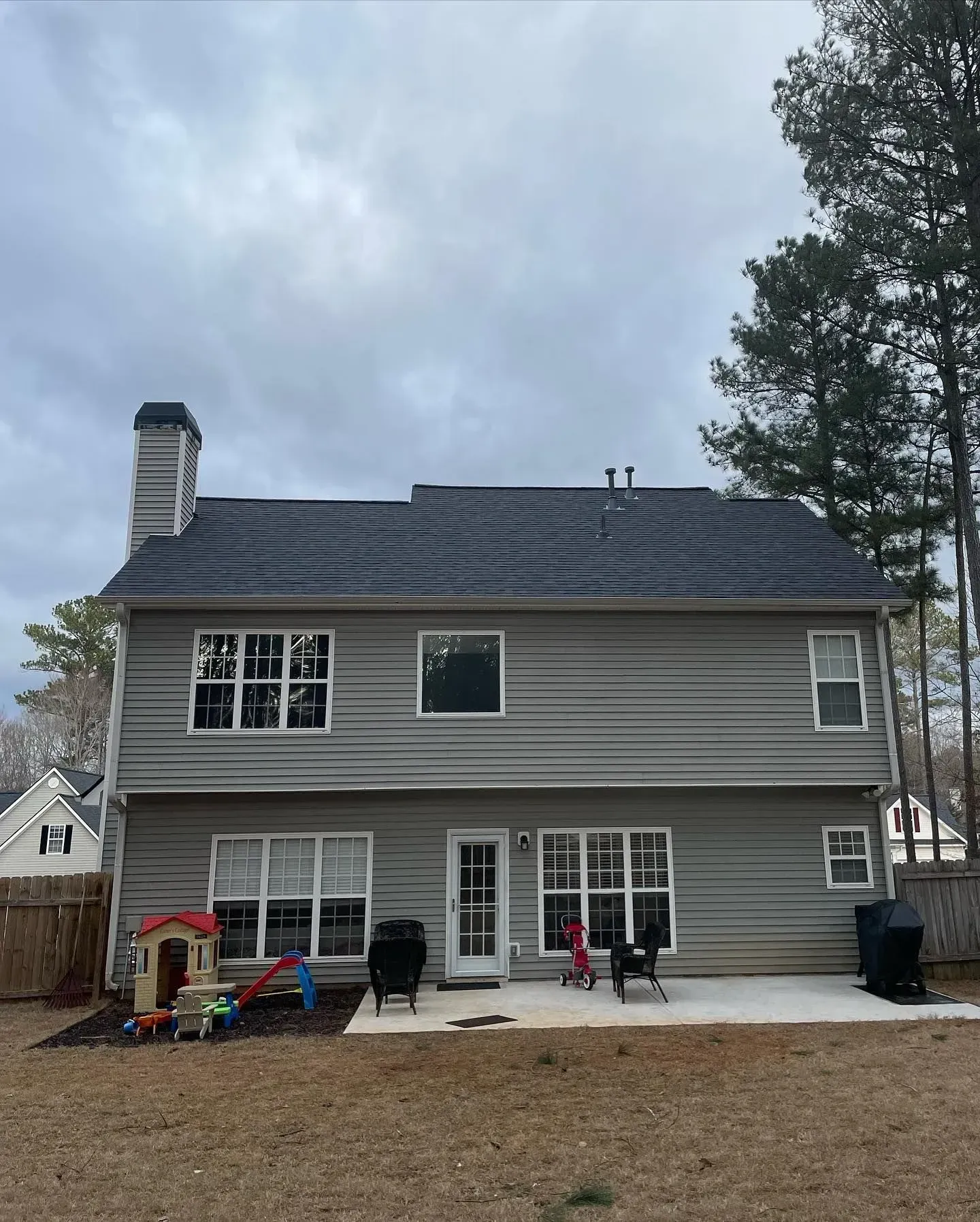 The back of a house with a playground in front of it.