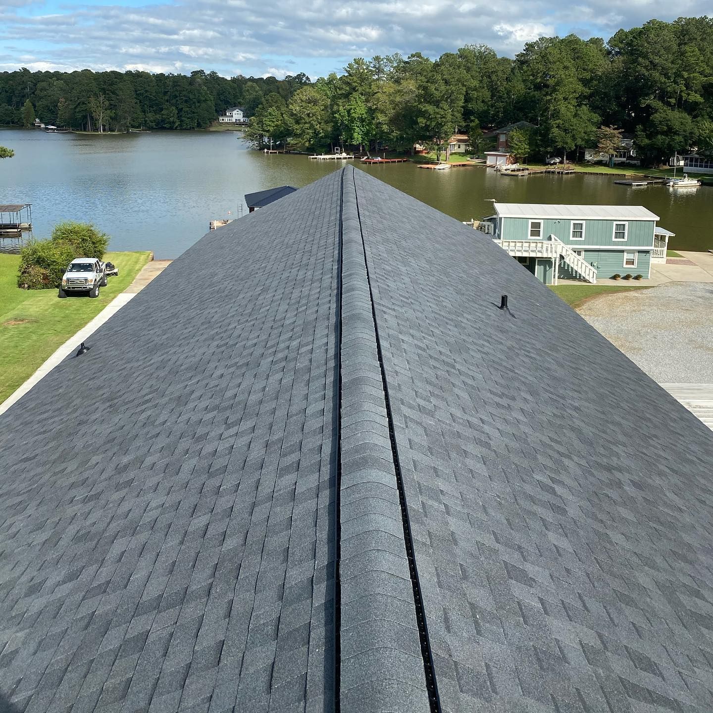A roof with a view of a lake and a house in the background.