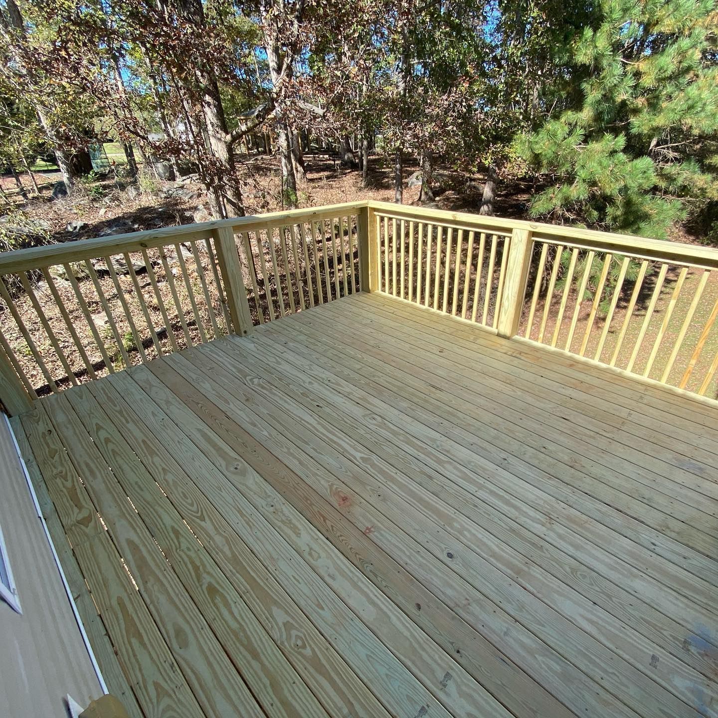 A wooden deck with a railing and trees in the background.