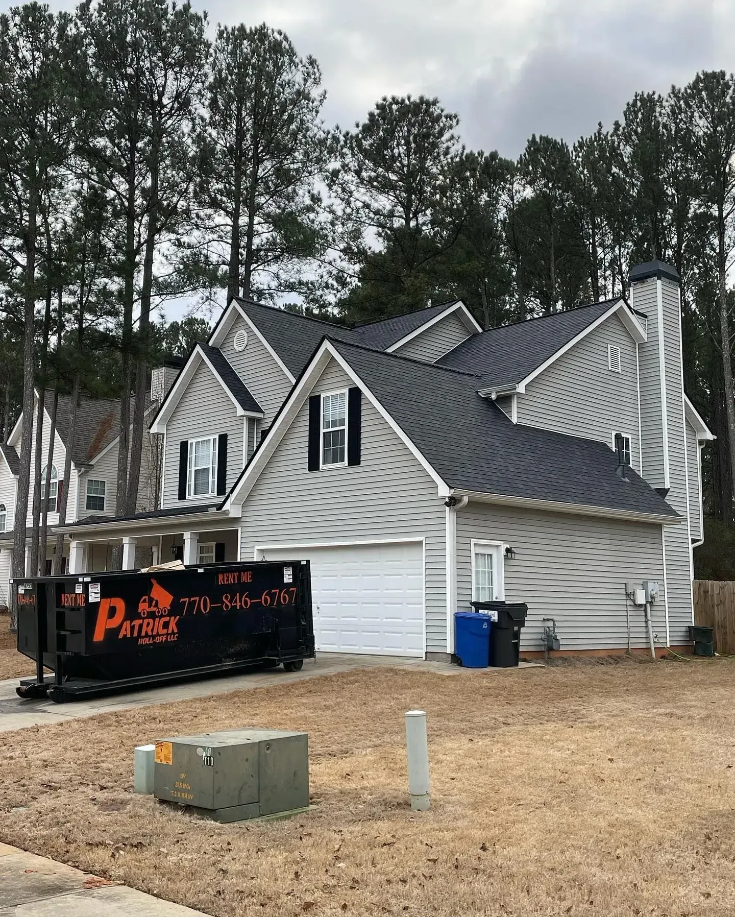 A large white house with a dumpster in front of it.