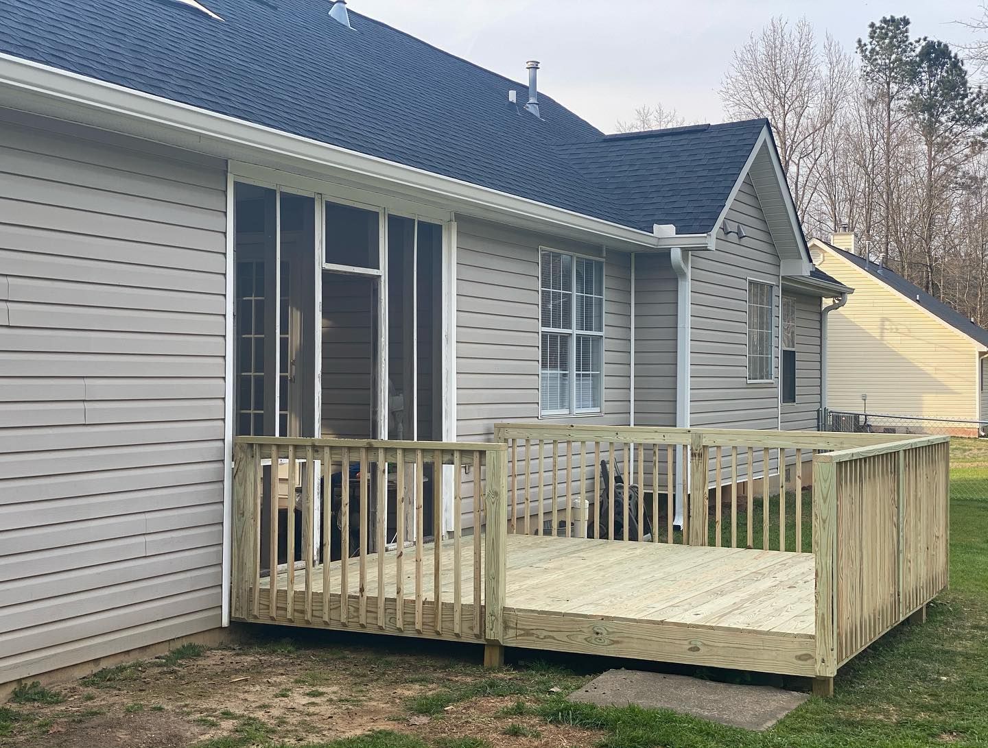 A house with a screened in porch and a wooden deck.