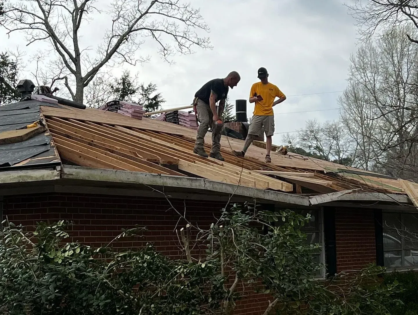Two men are working on the roof of a house.