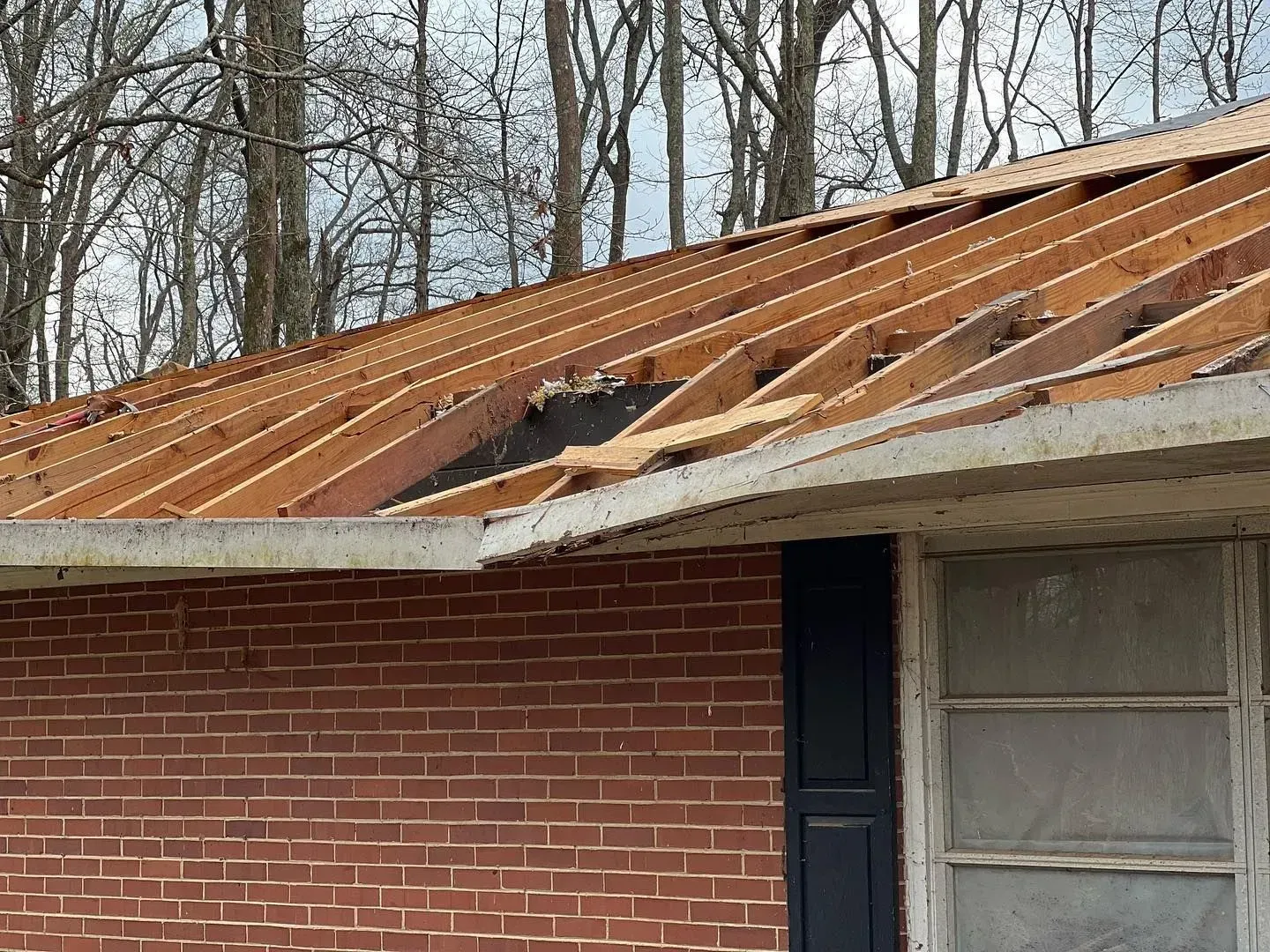 A brick house with a roof that has been damaged by a storm.