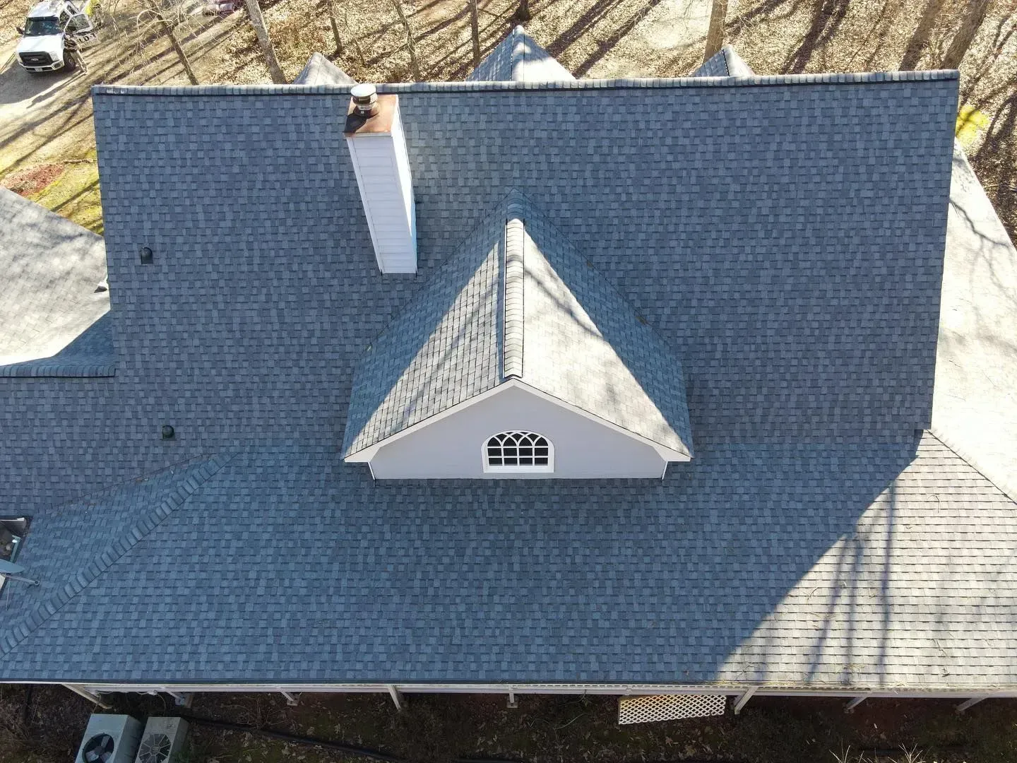 An aerial view of a house with a blue roof and a white chimney.