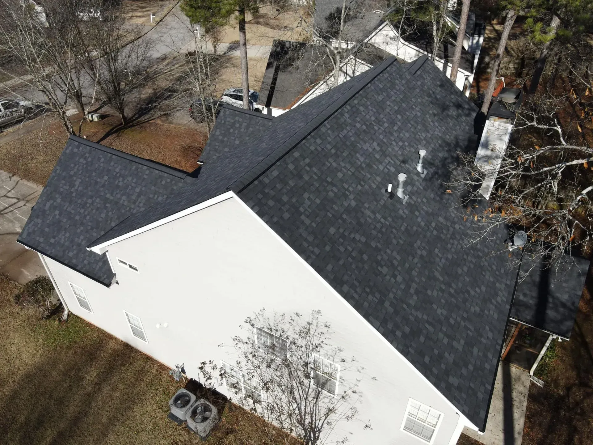 An aerial view of a white house with a black roof.