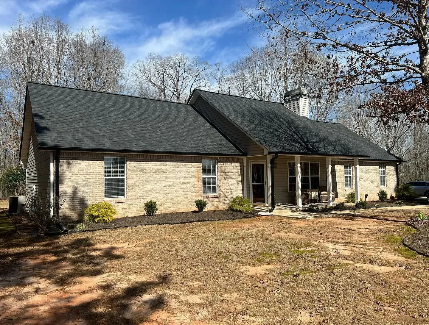 A large brick house with a black roof and a porch.