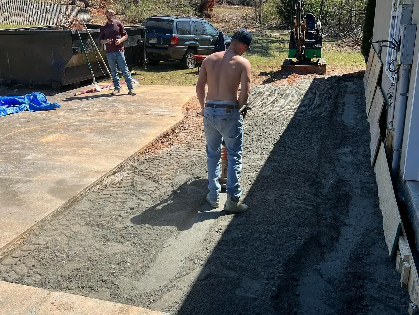 A shirtless man is standing on a dirt road.