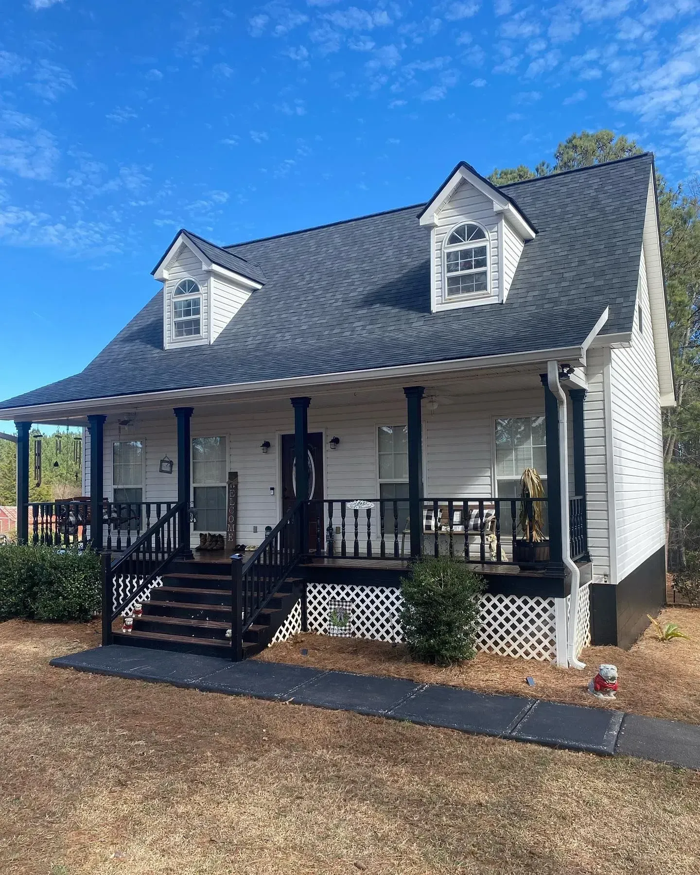 A white house with a black porch and a black roof.