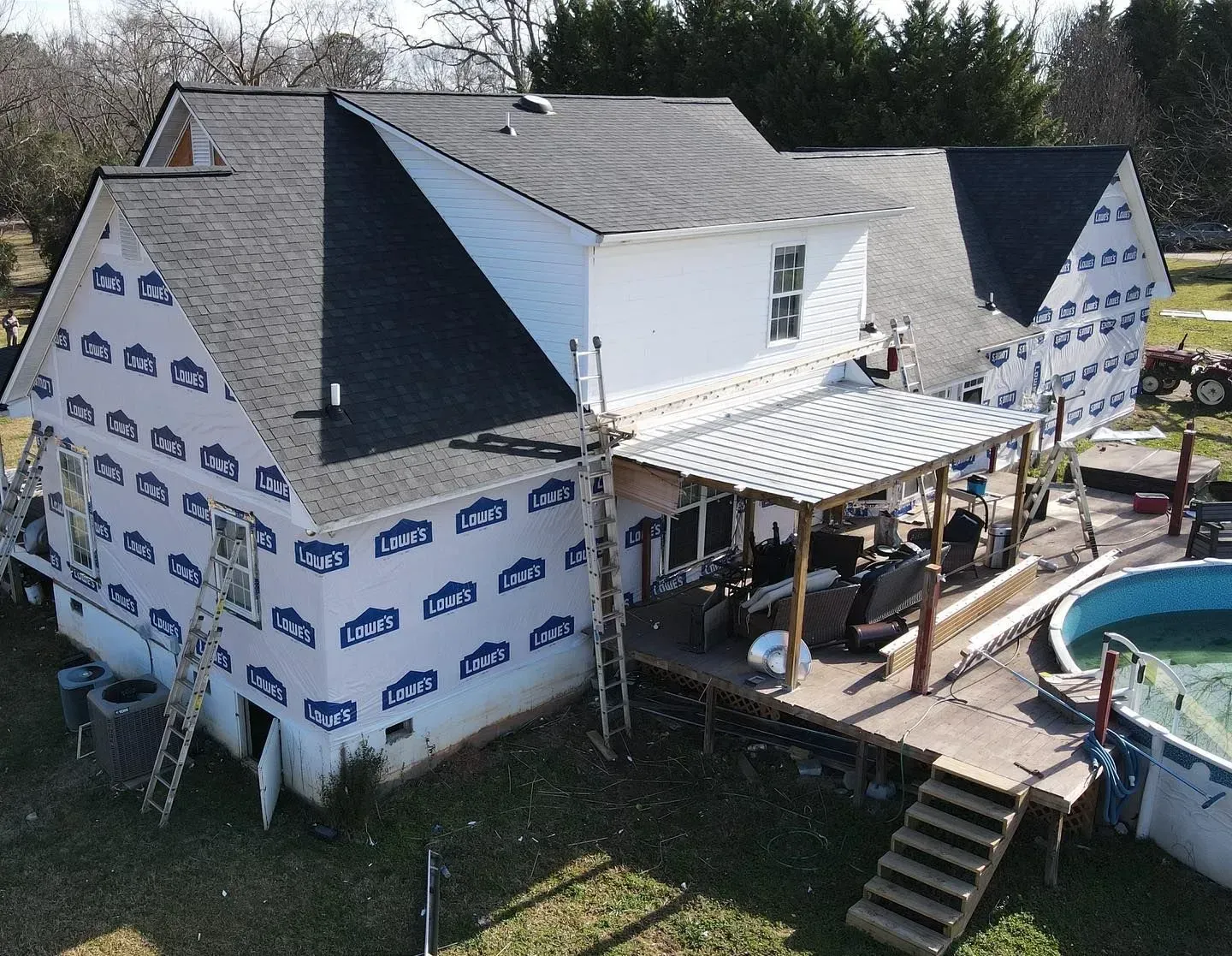 An aerial view of a house being remodeled with a pool in the backyard.