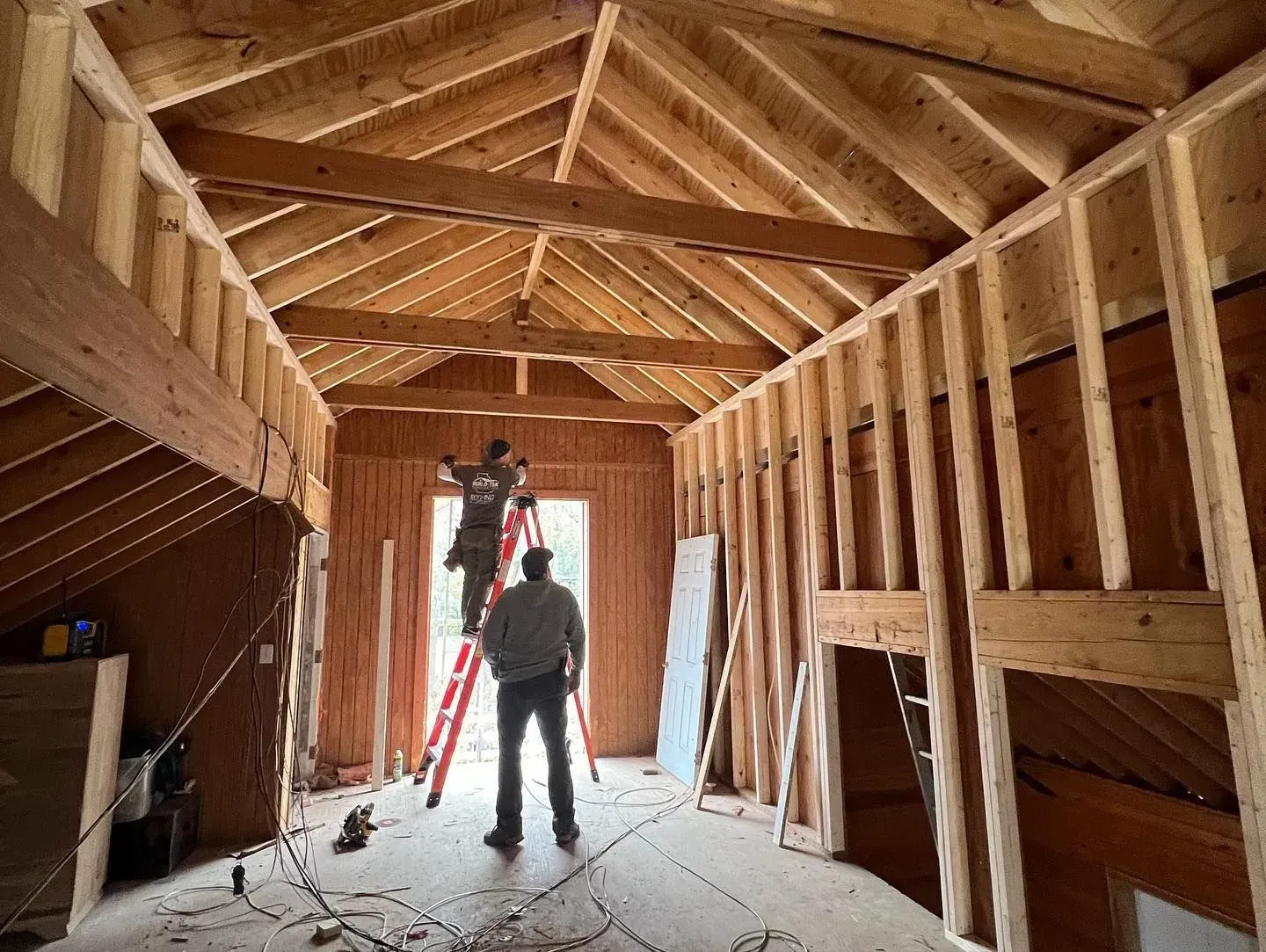 A man is standing on a ladder in a room under construction.