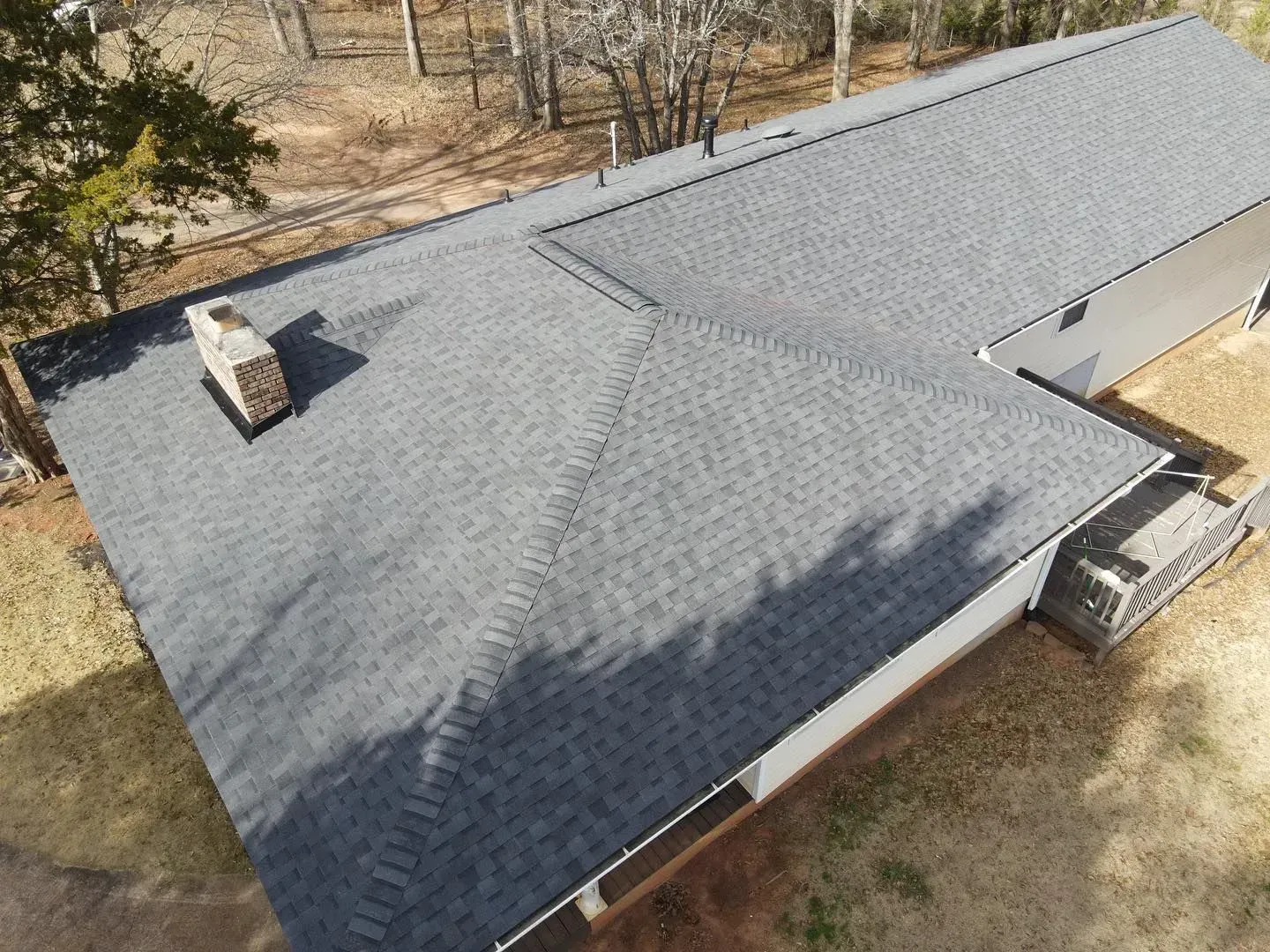 An aerial view of a house with a new roof and chimney.