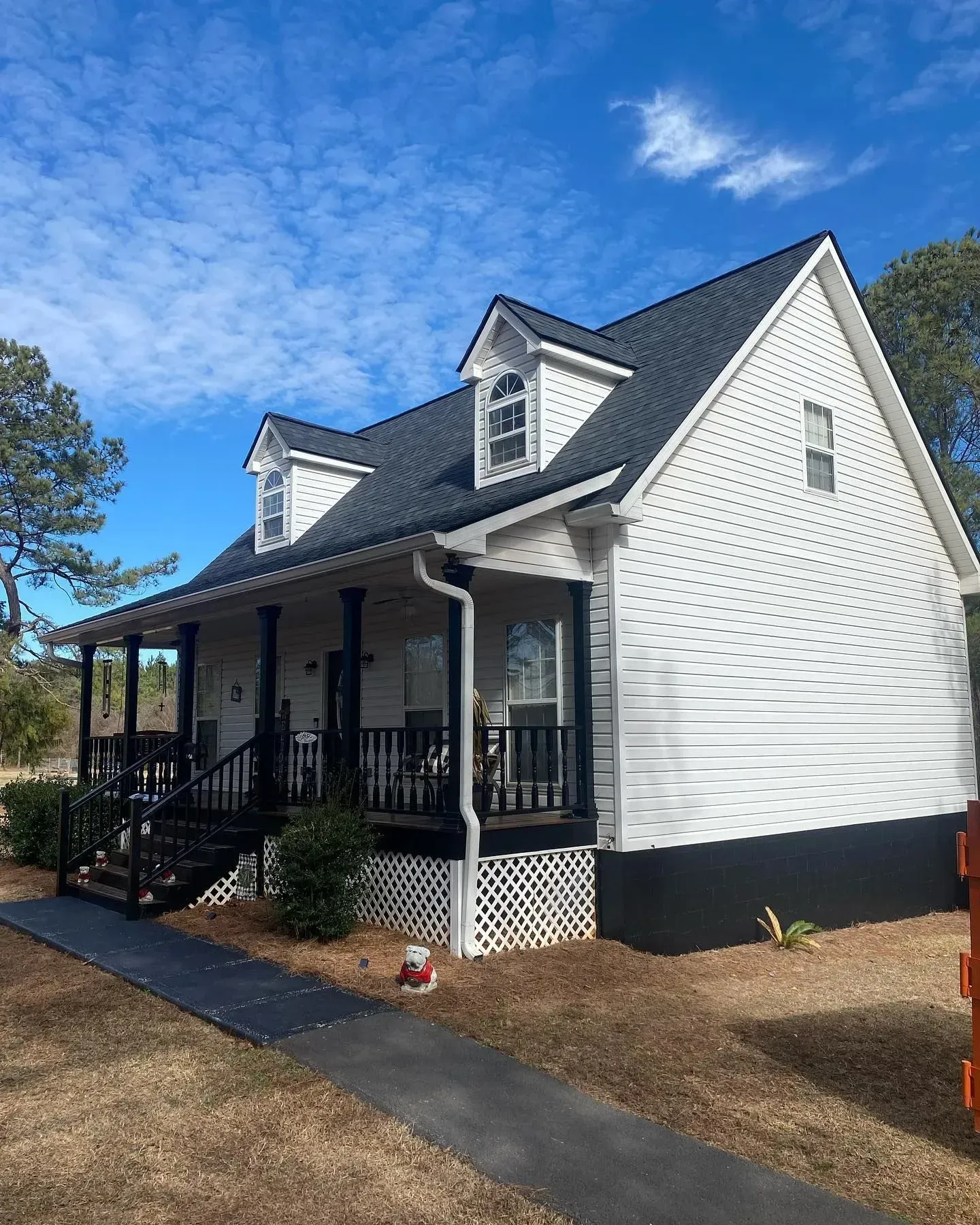 A white house with a black roof and a porch.