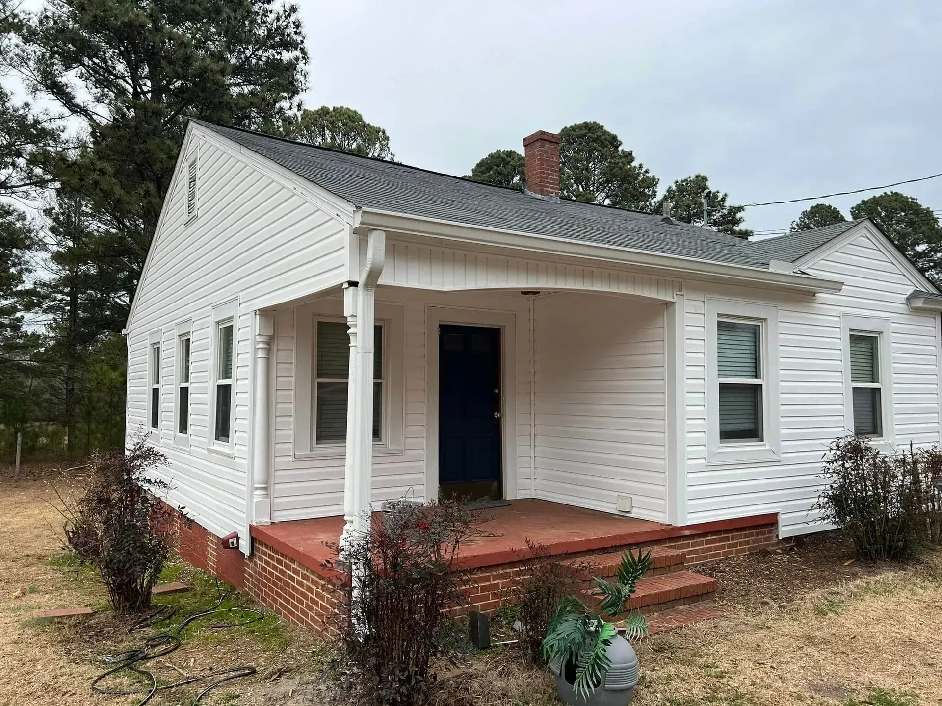 A small white house with a blue door and a porch.