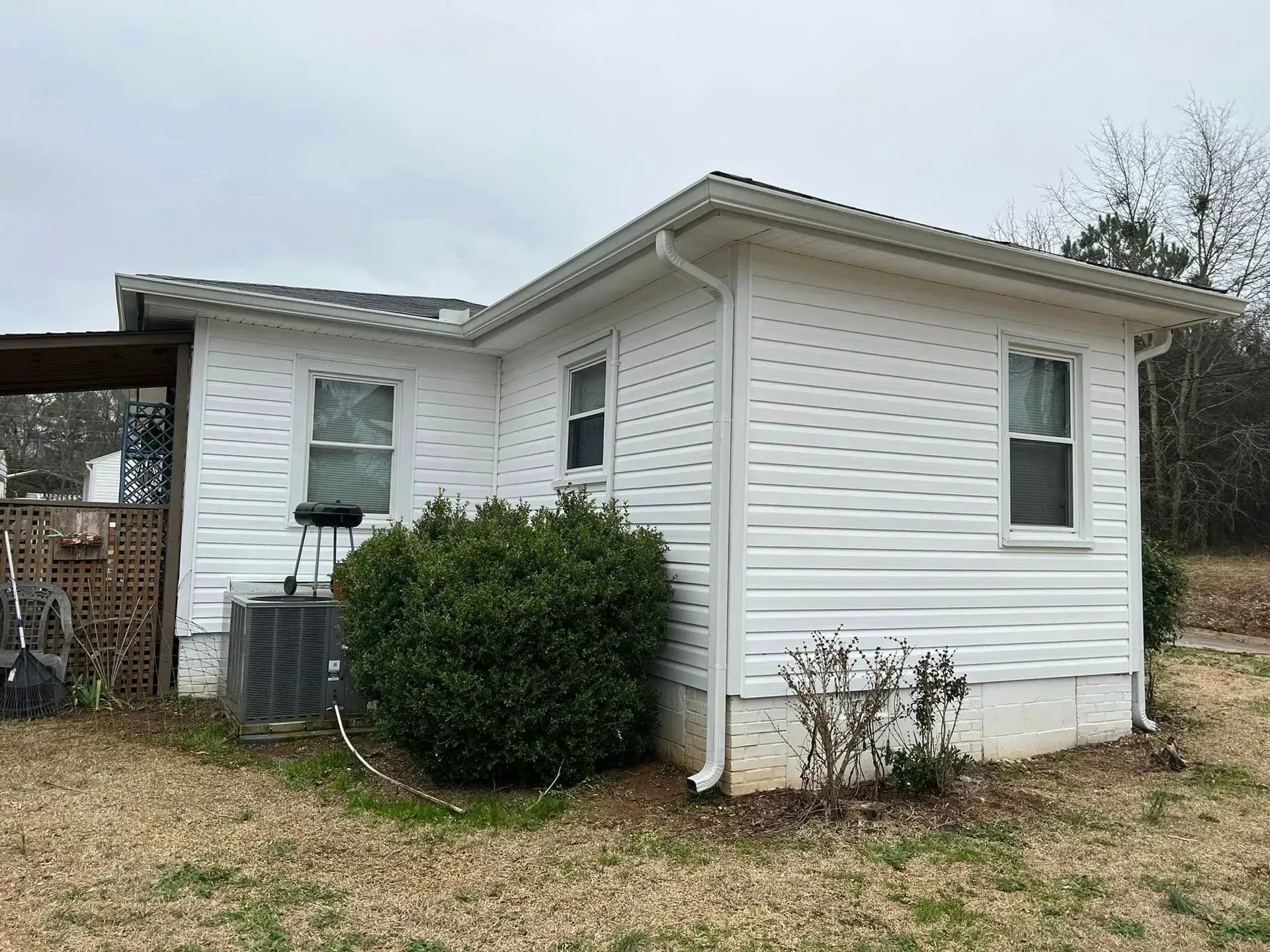 A small white house is sitting on top of a dirt field.