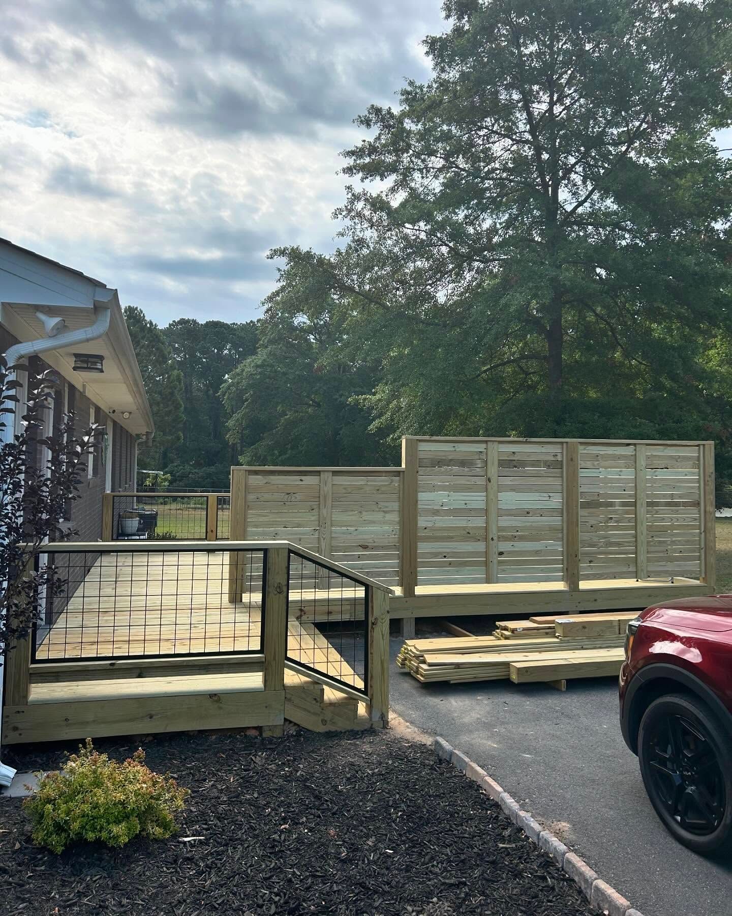 A red truck is parked in front of a wooden deck.