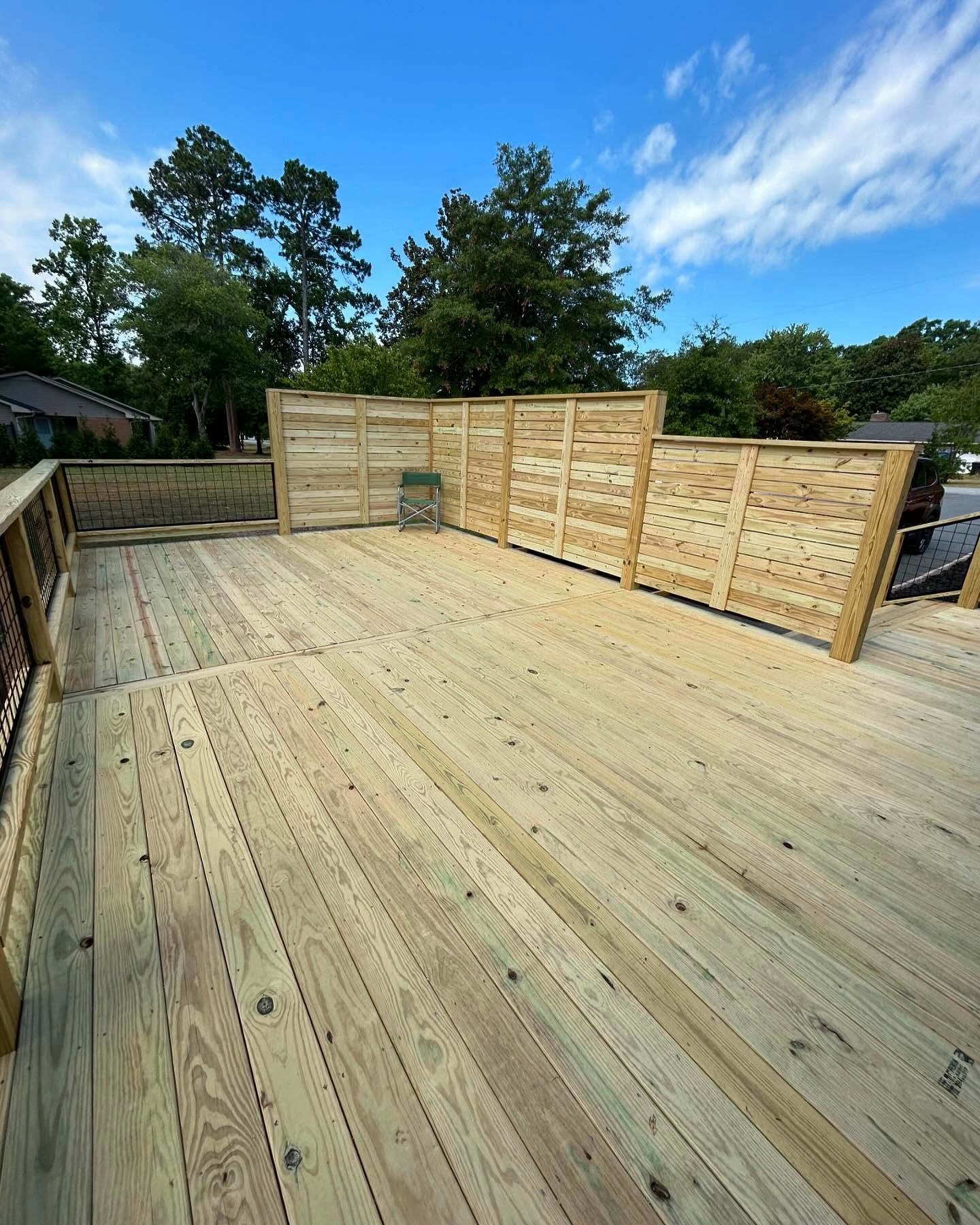 A wooden deck with a wooden fence and trees in the background.