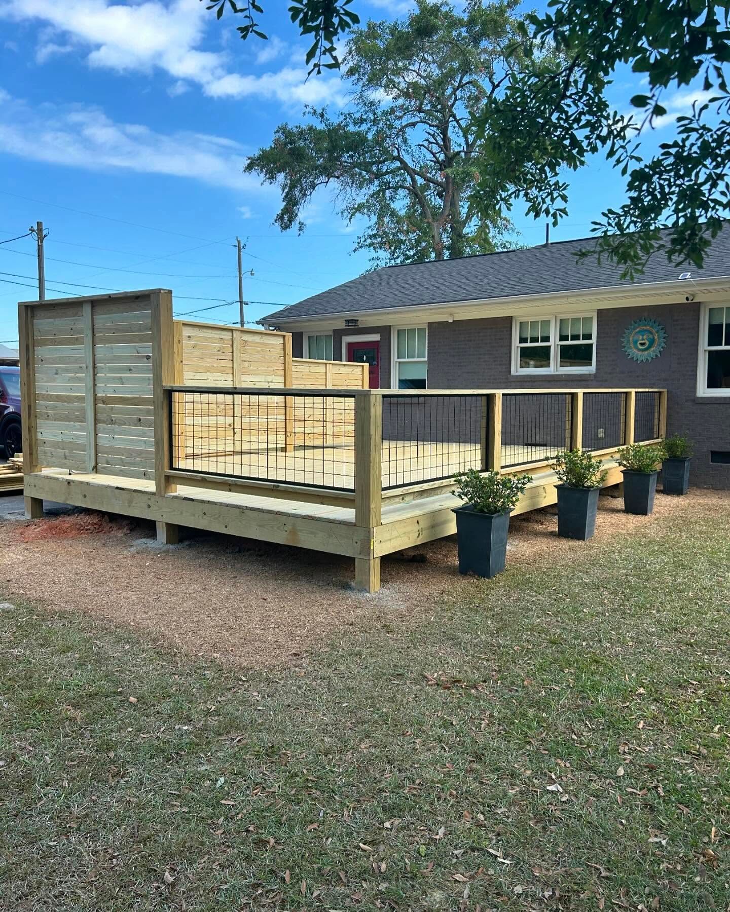 A wooden deck is sitting in front of a house.