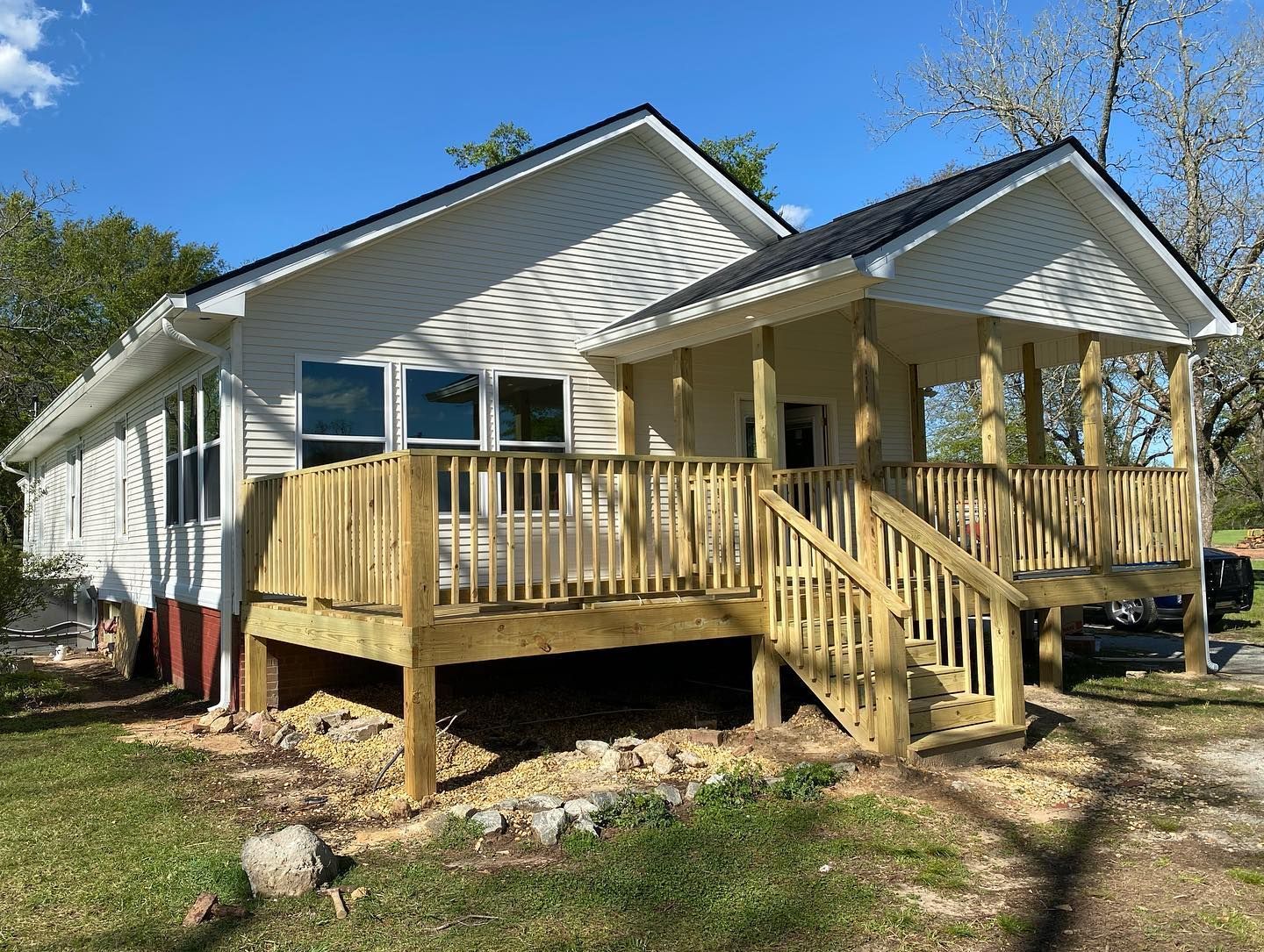 A white house with a wooden deck and stairs.