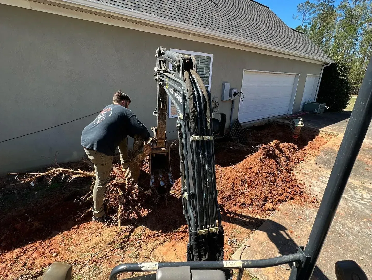 A man is digging a hole in the dirt in front of a house.