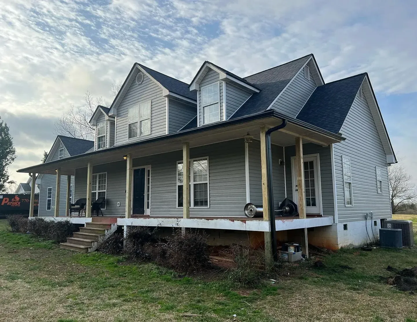 A large white house with a porch and a black roof.