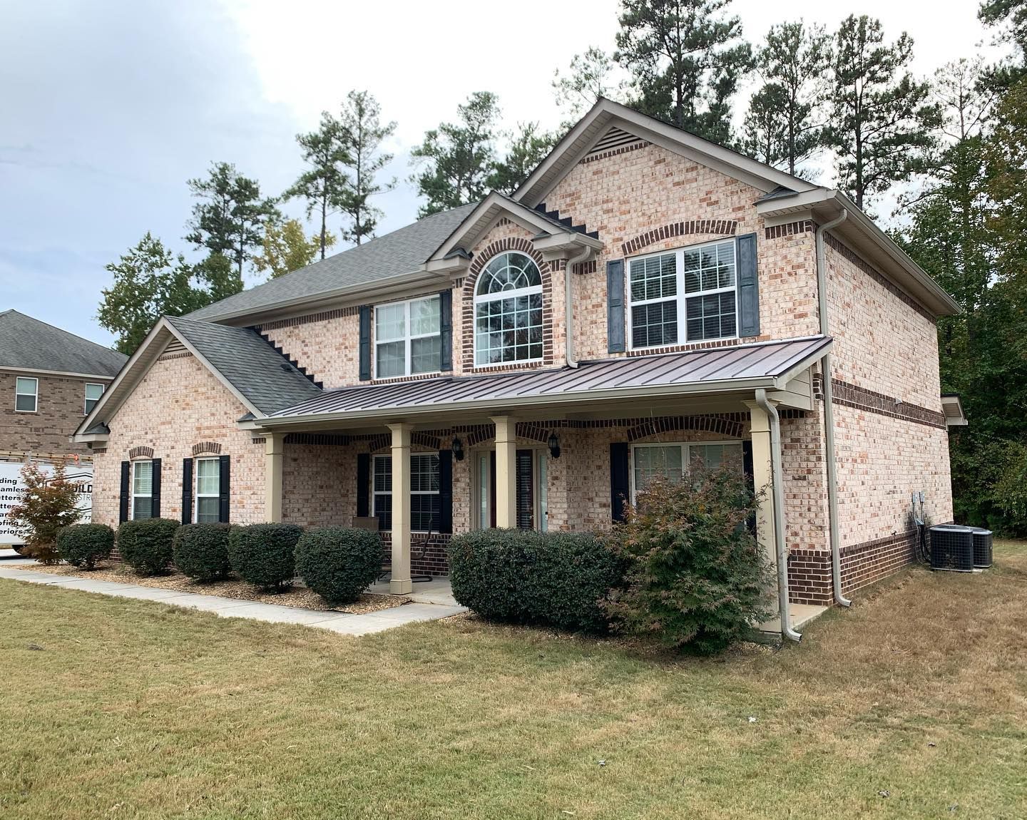 A large brick house with a metal roof and a porch.