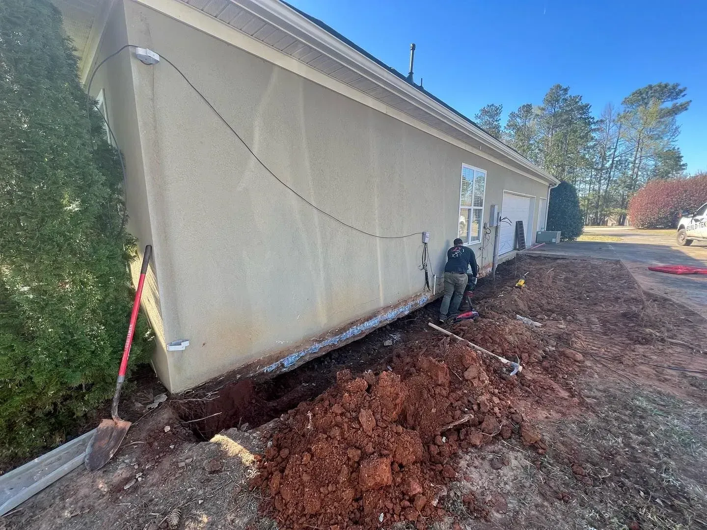 A man is digging a hole in front of a building.