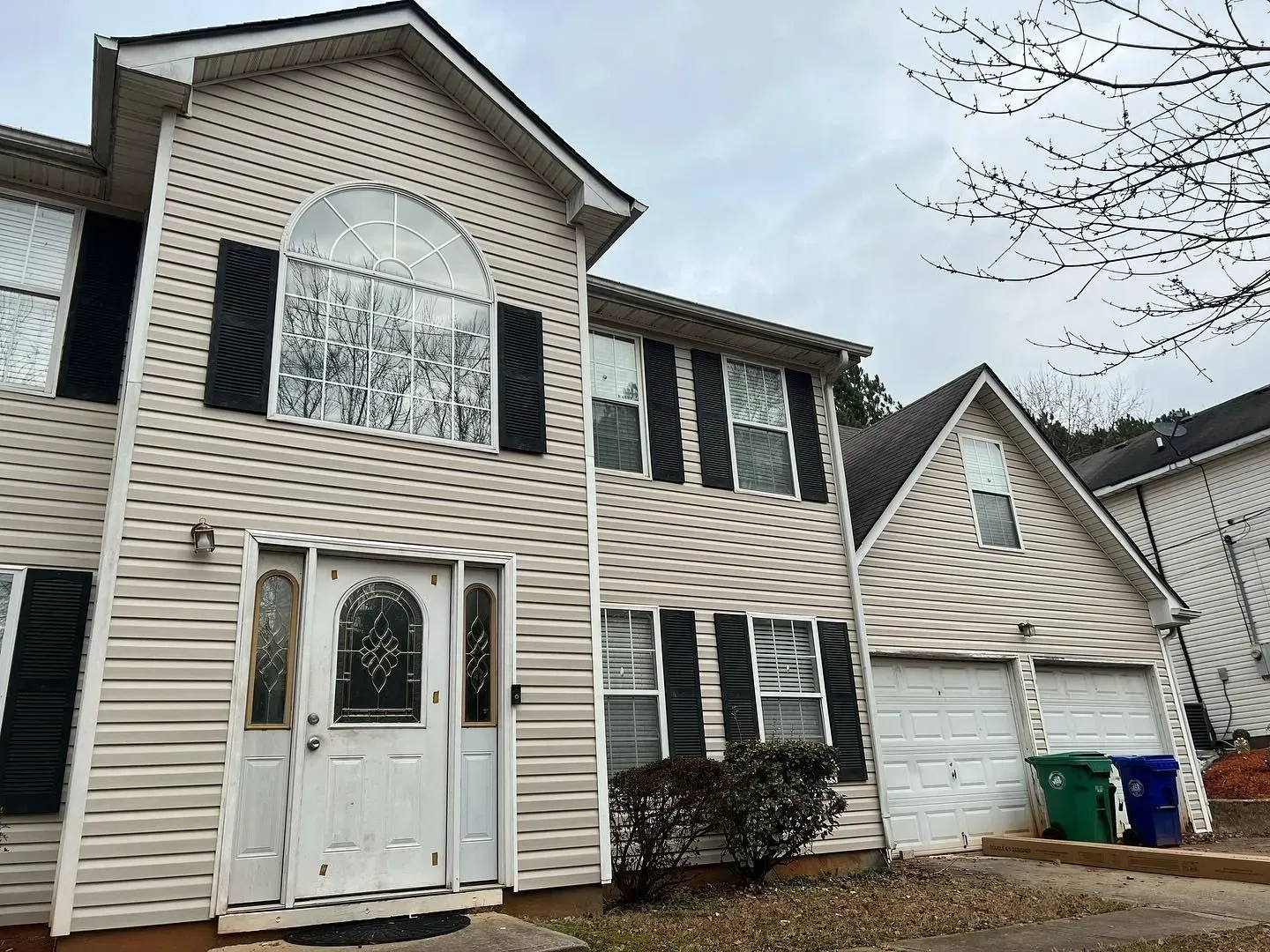 A large white house with black shutters is for sale.