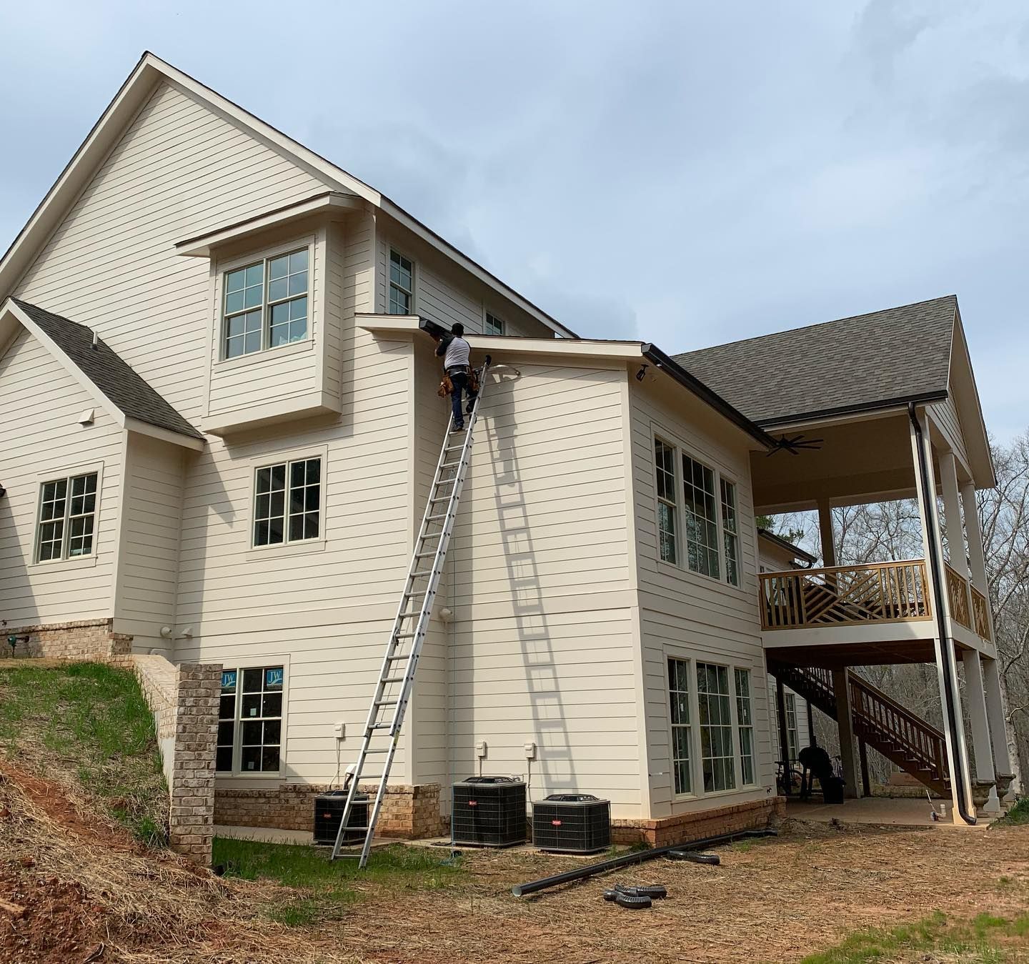 A man on a ladder is painting the side of a house