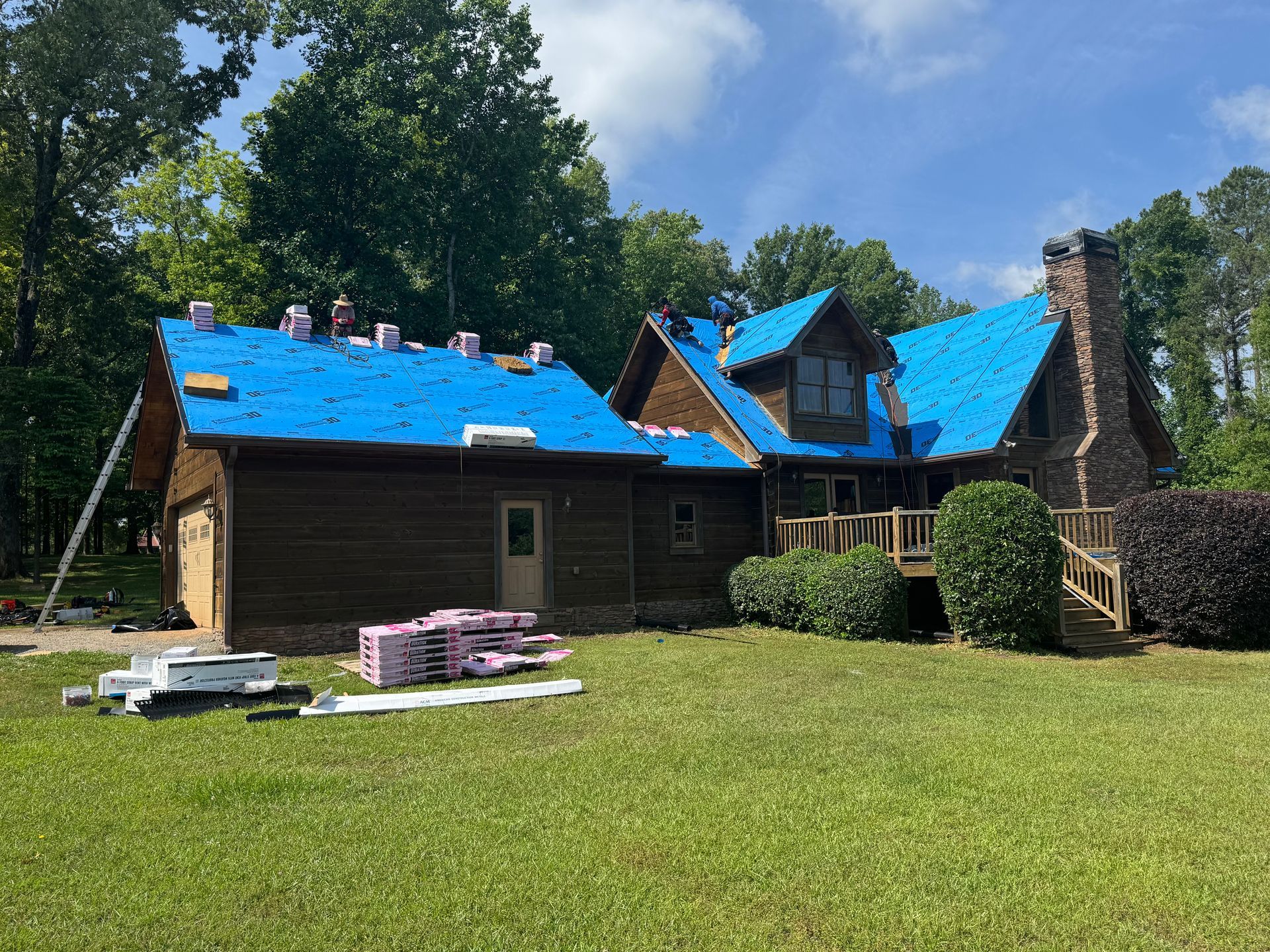 A large log cabin with a blue roof is being remodeled.