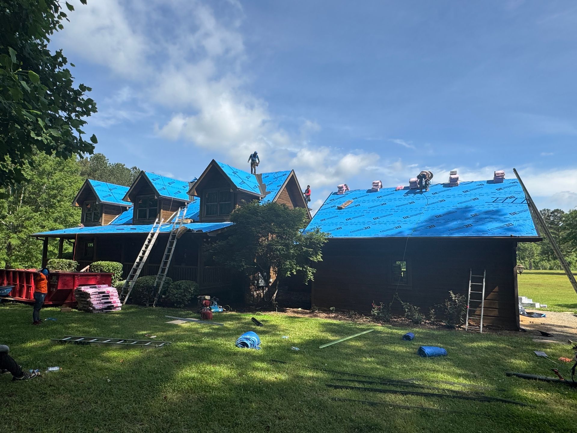 A large house with a blue roof is being remodeled.