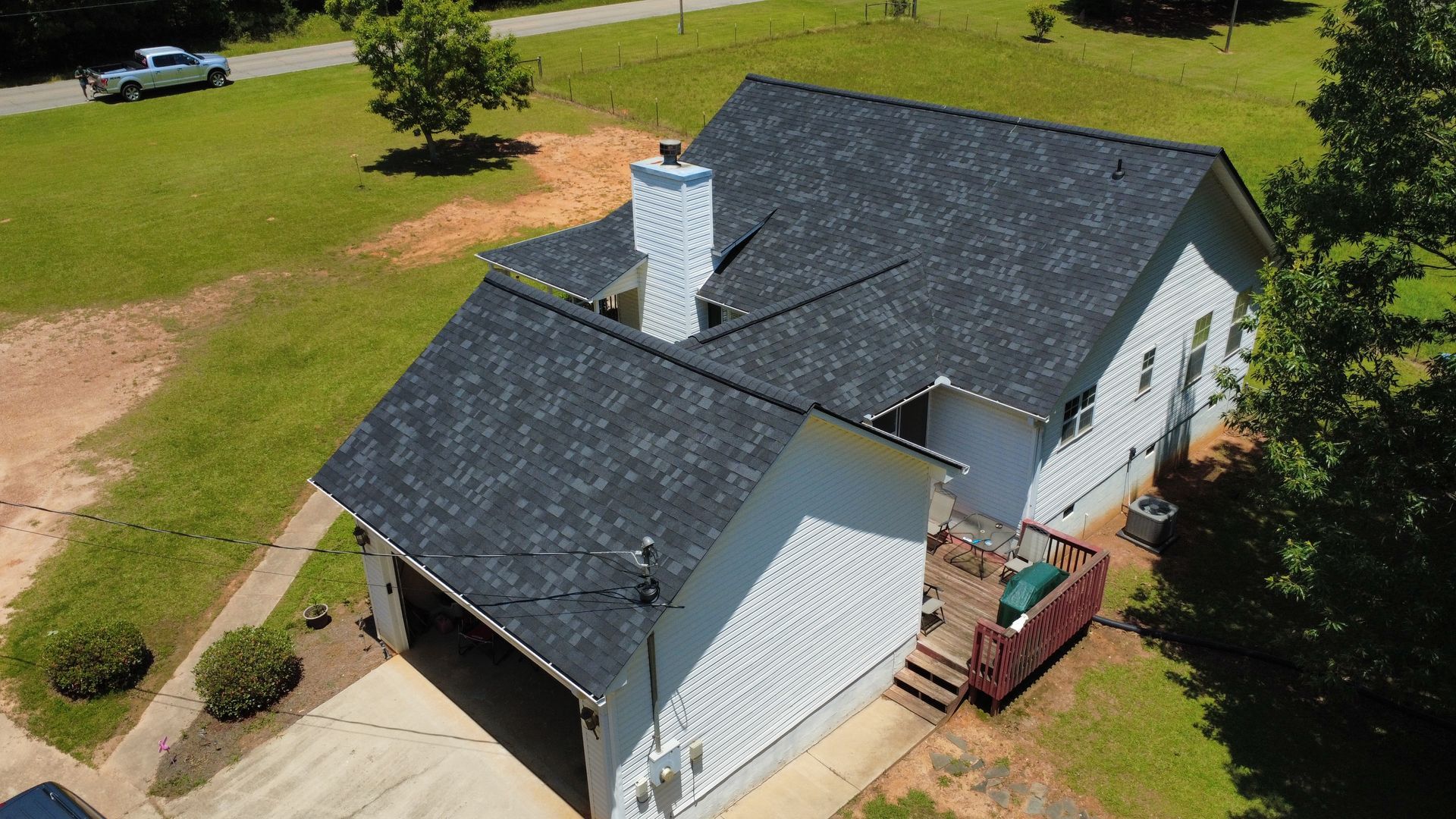 An aerial view of a white house with a black roof.