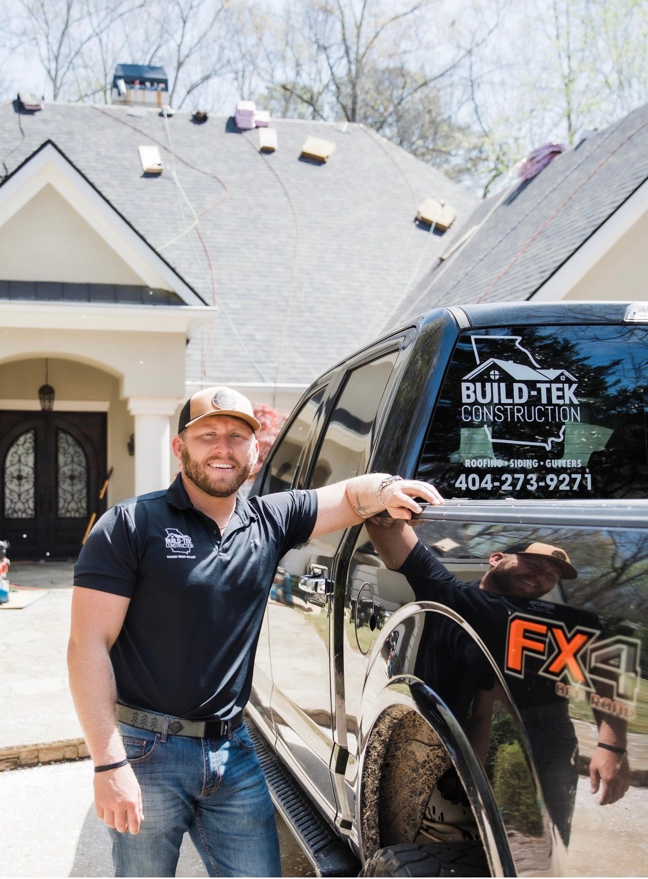 Two men are standing in front of a house holding a sign.