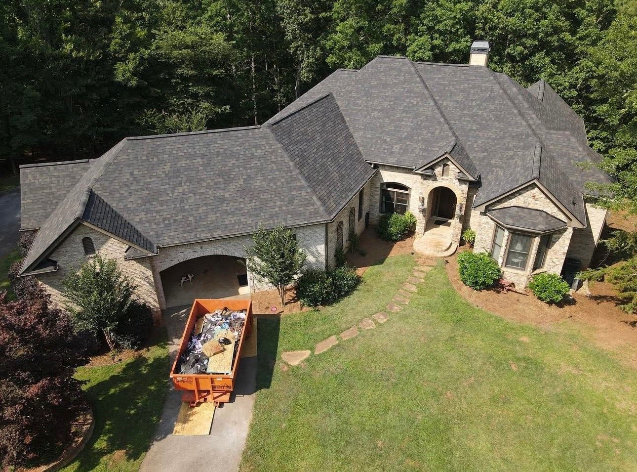 An aerial view of a large house with a dumpster in front of it.
