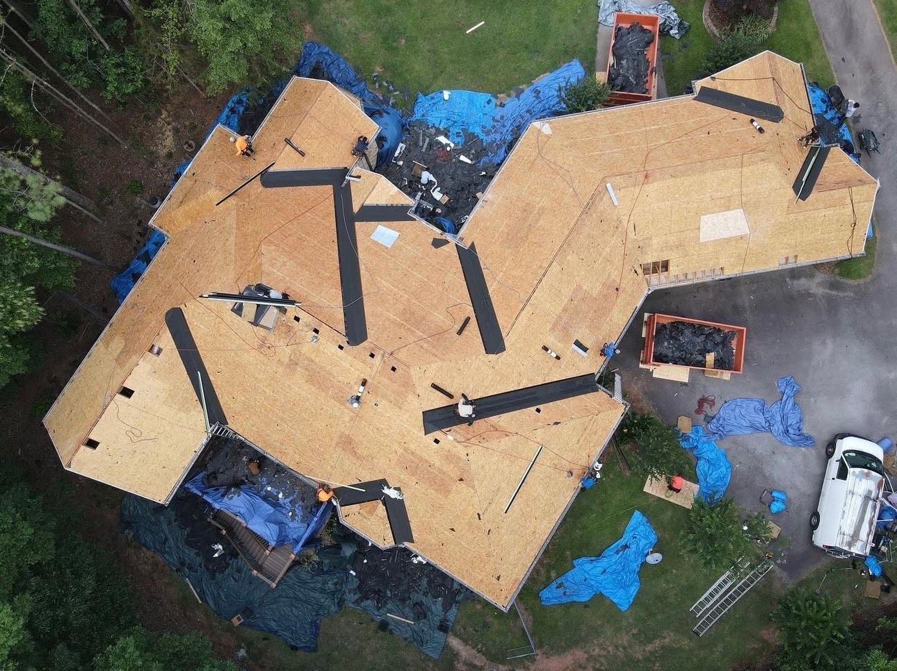 An aerial view of a house under construction with a roof being installed.