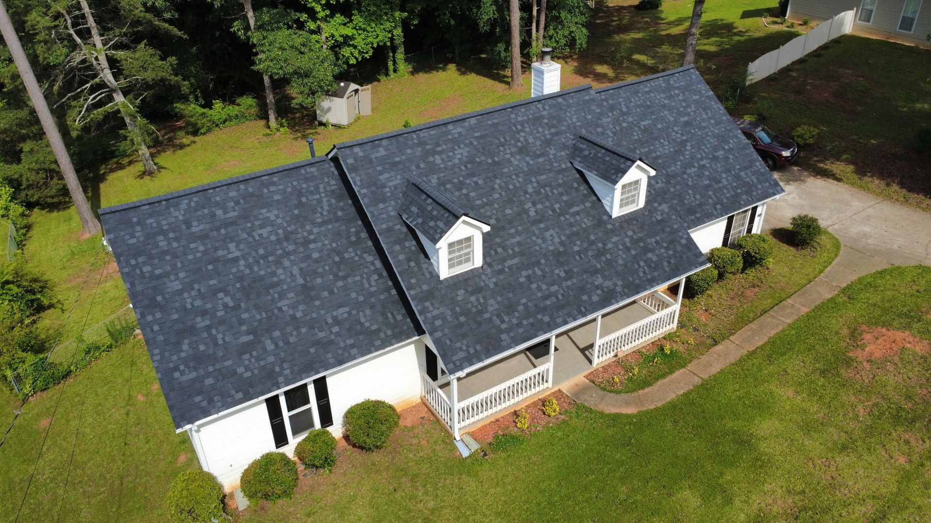 An aerial view of a white house with a black roof.