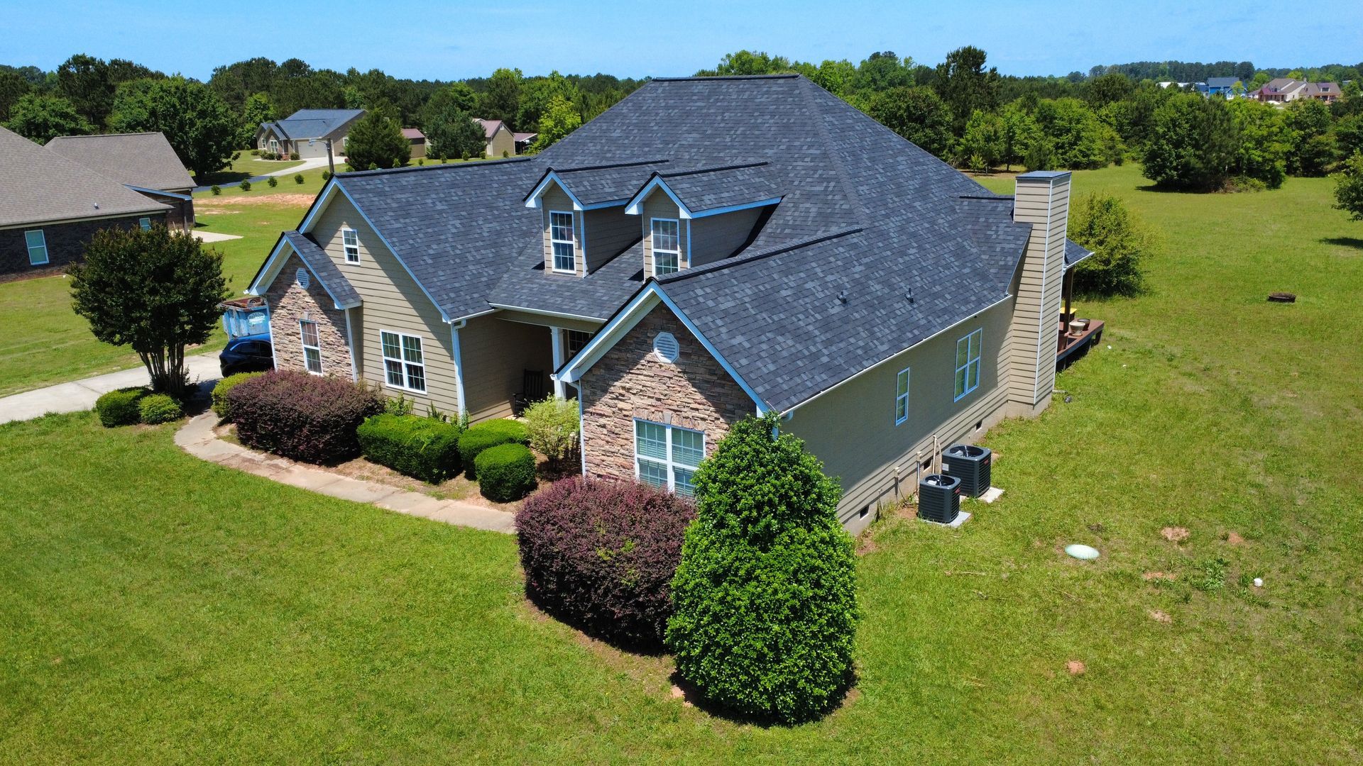 An aerial view of a large house with a blue roof in a residential area.