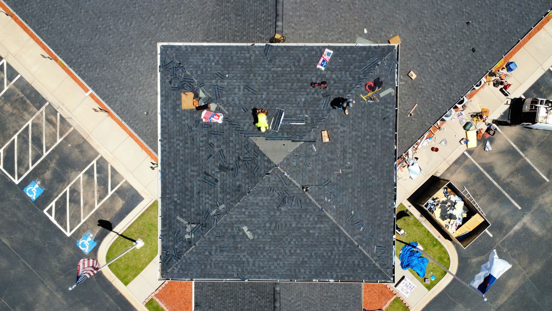 An aerial view of a roof being repaired in a parking lot.