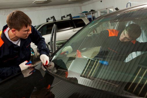Techs completing auto glass repairs on windshield
