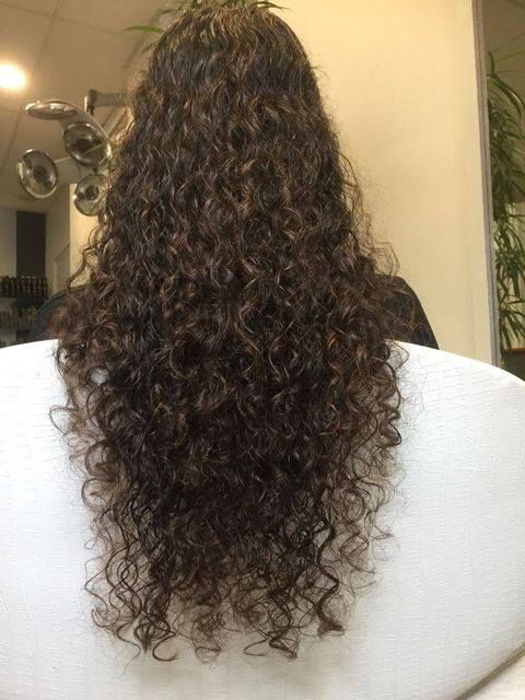 A Woman With Long Curly Hair Is Sitting In A Chair — Fuse Hair & Beauty In Darwin City, NT